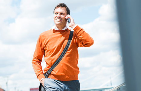Man in Orange Shirt Talking on Mobile Phone on Sunny Day