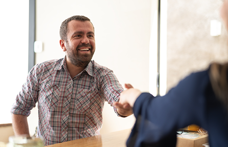 Man in Plaid Shirt Smiling Whiling Shaking Consultants Hand