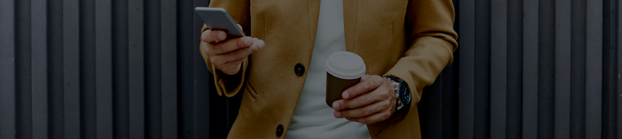 Person Holding Coffee Cup and Viewing U.S. Dollar Accounts on Mobile Device