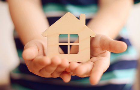 Person Holding Small Wooden Carving of a House.png