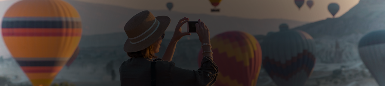 Person Taking Photos of Hot Air Balloons from Mountain.png