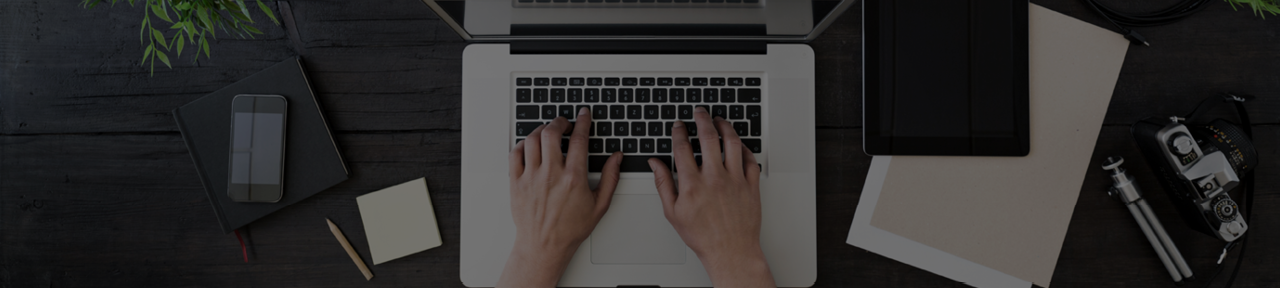 Person Typing on Laptop Surrounded by Other Various Electronics