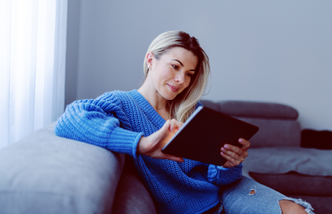 Woman Sitting on Couch and Browsing Mortgage Rates on Tablet