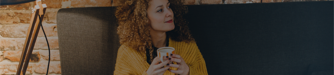 Woman Smiling while Holding Teacup and Sitting on Sofa