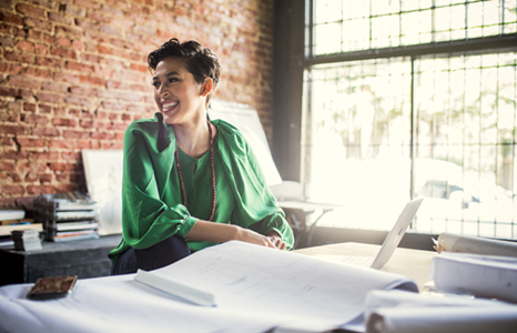 Woman in Green Shirt Sitting at Desk Covered in Papers