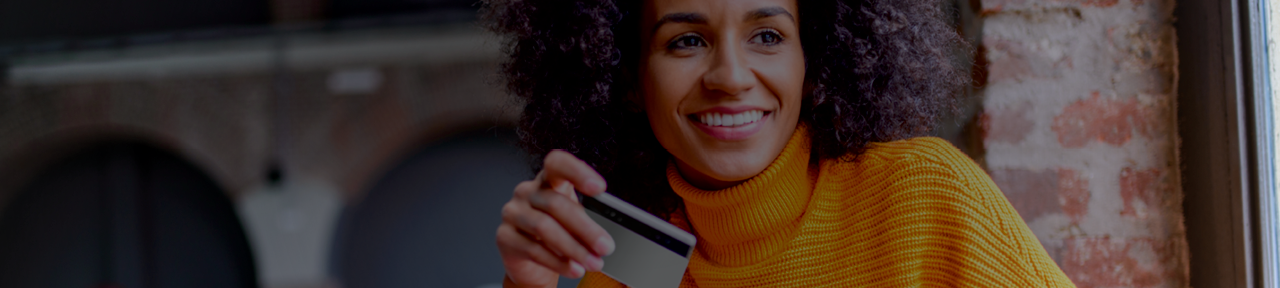 Woman in Yellow Sweater Smiling and Holding Creative Arts Financial Debit Card