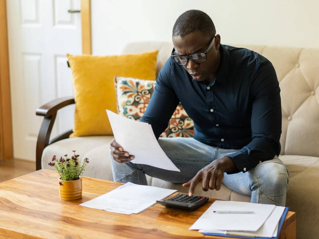 Man Using Calculator While Looking at Paperwork