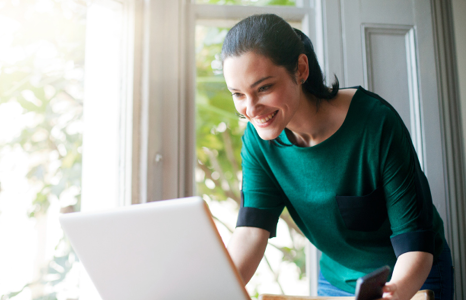 Woman Using Laptop to Access Market Insights with XE