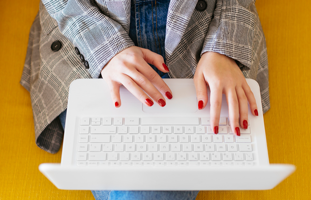 Woman Sitting on Yellow Couch Typing on Laptop