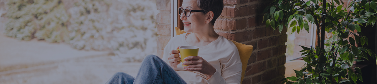 Person holding yellow coffee mug and sitting in window