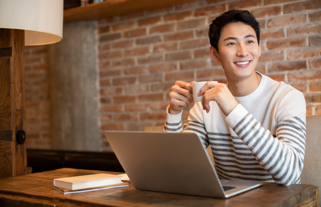 Person Sitting with Laptop at Coffee Shop