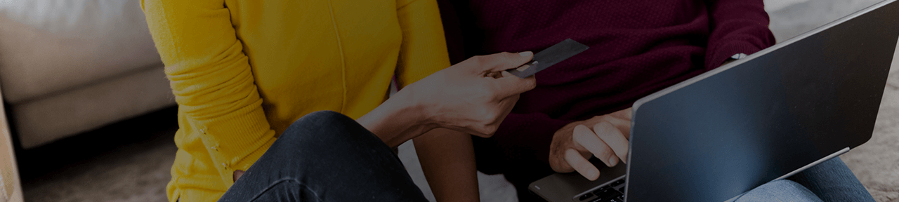 Woman in yellow sweater logging into online banking with debit card
